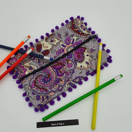 Pencil case in purple pattern fabric with bobble trim. 