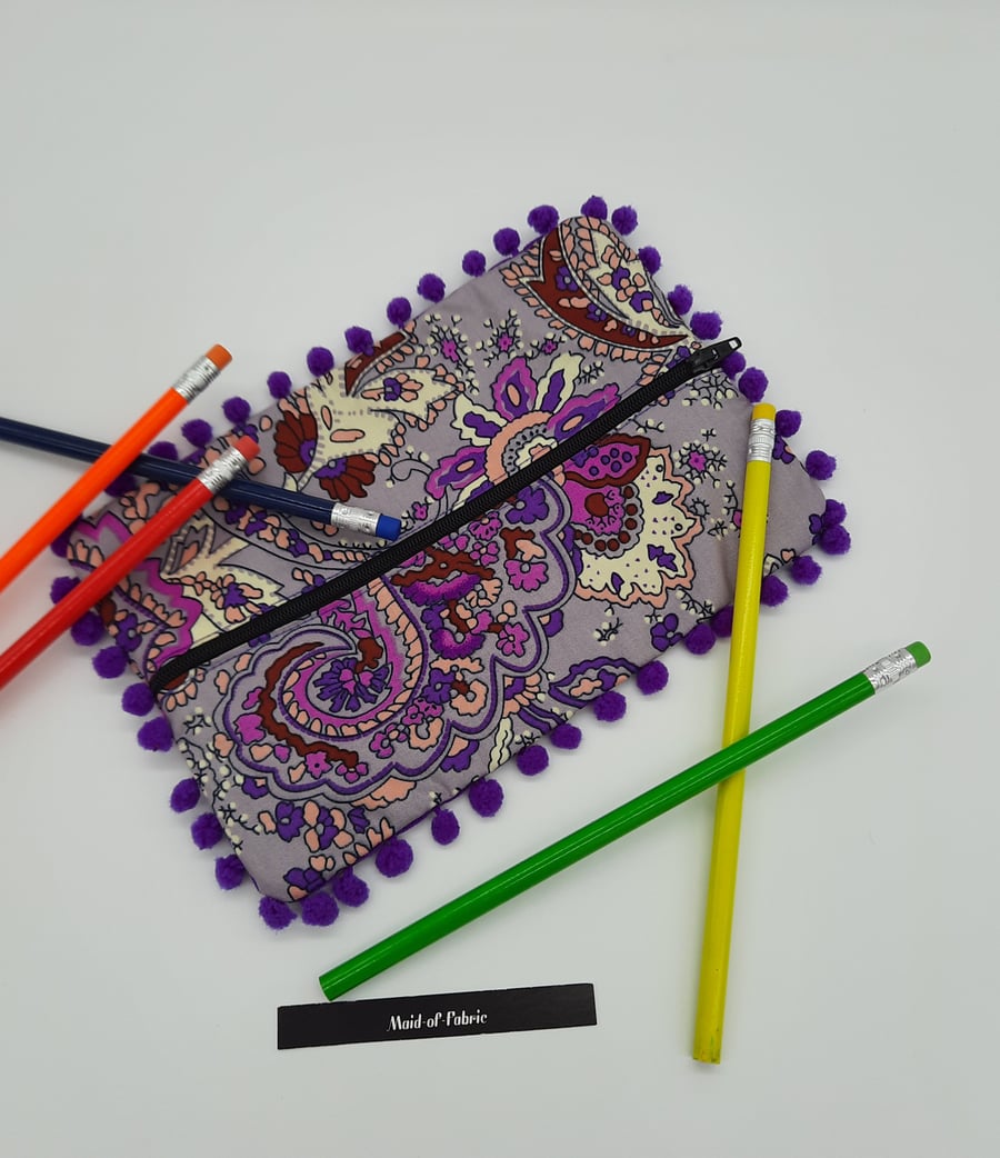 Pencil case in purple pattern fabric with bobble trim. 