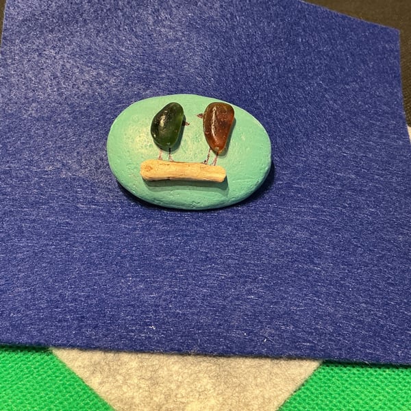 Hand painted pebble with 2 birds on a branch.