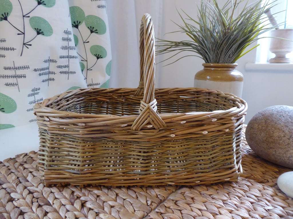 A handmade rectangular willow basket with a handle.