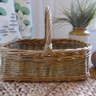 A handmade rectangular willow basket with a handle.