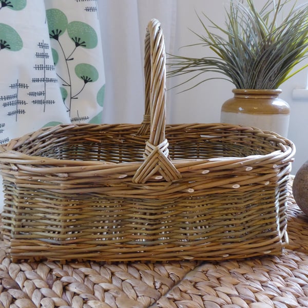 A handmade rectangular willow basket with a handle.