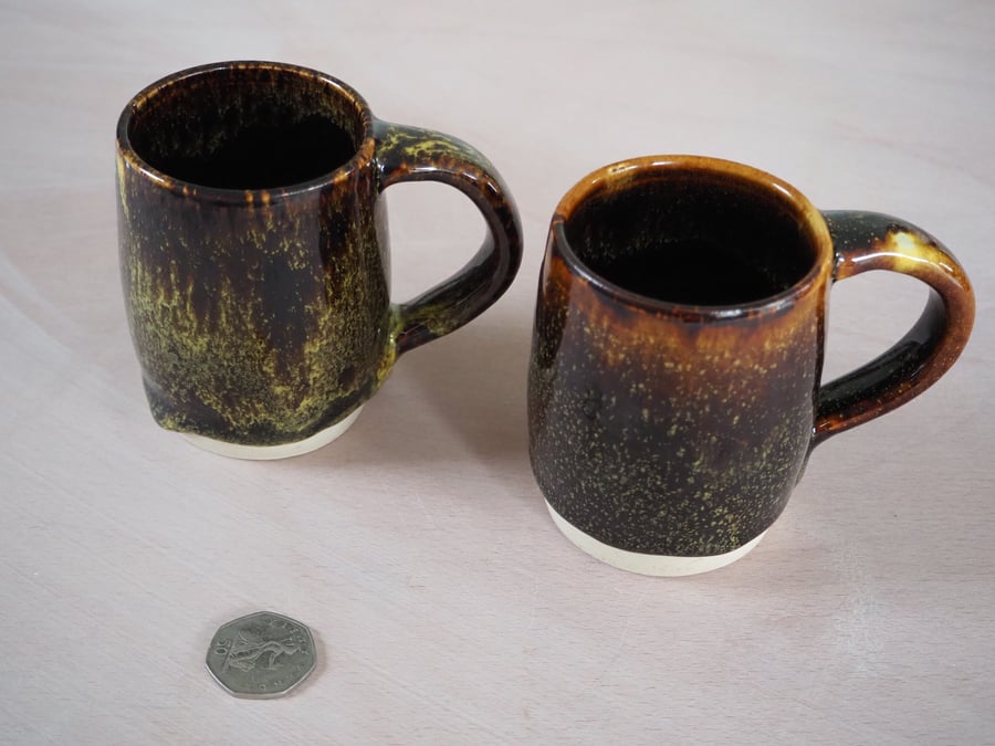 Set of two pottery mugs finished in a multi-colour glaze combination.