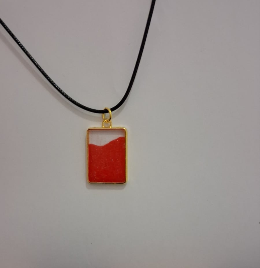 Handmade epoxy resin red and clear rectangular pendant on  black waxed cord