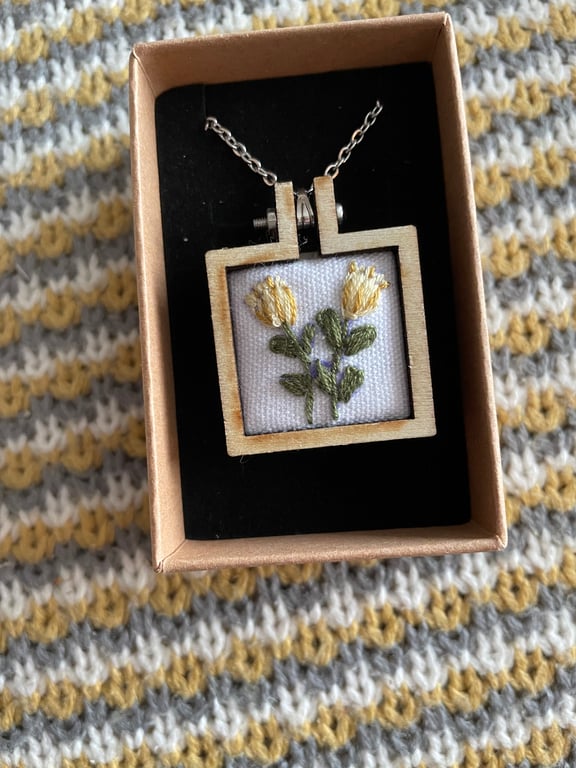 Hand embroidered Yellow flowers and set in a wooden necklace.