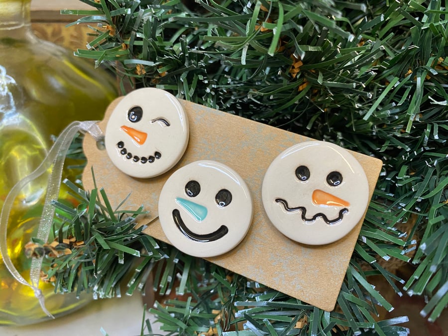 Set of three pottery snowmen magnets on a Christmas gift tag