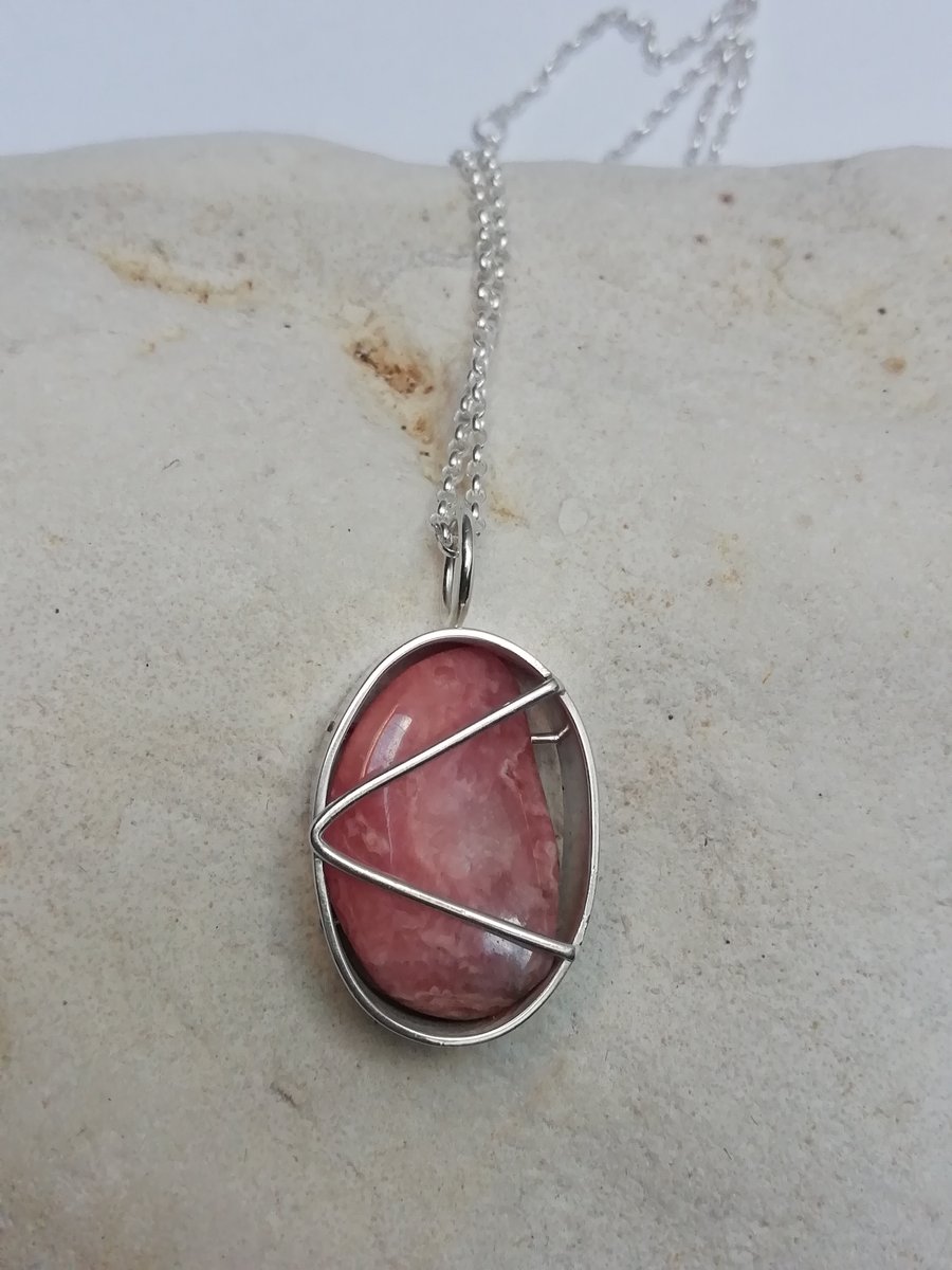 Polished Rhodochrosite in an Oval Cage.
