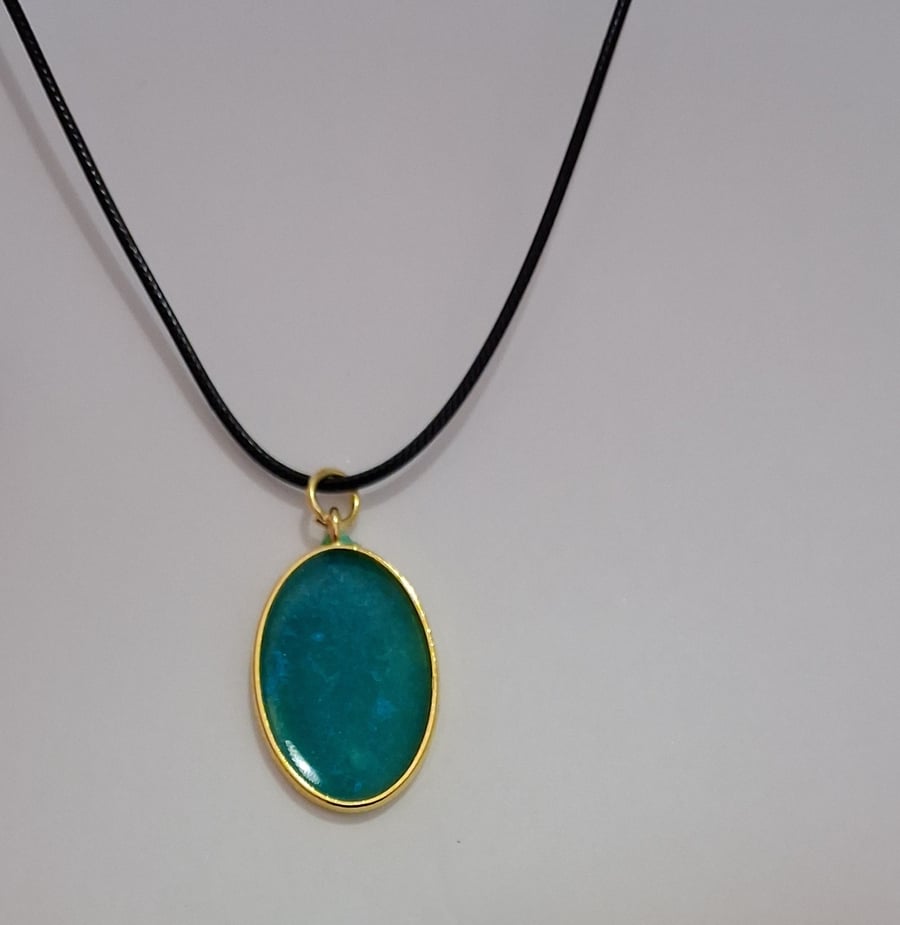 Handmade epoxy resin teal shimmer oval pendant on  black waxed cord