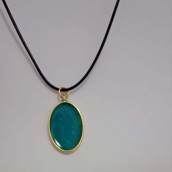 Handmade epoxy resin teal shimmer oval pendant on  black waxed cord
