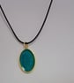 Handmade epoxy resin teal shimmer oval pendant on  black waxed cord