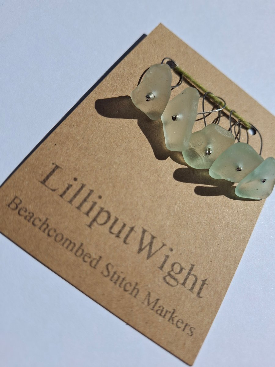 Five sea glass stitch markers in shades of sea foam