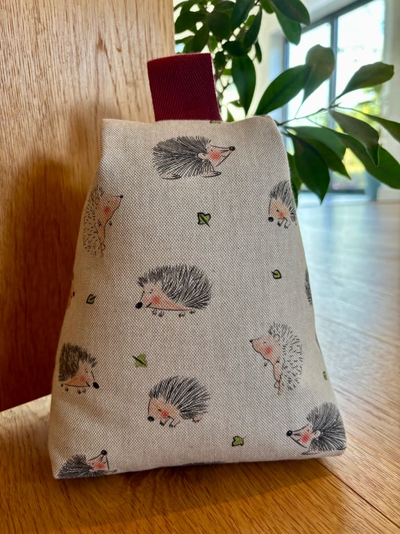 Cotton rich fabric doorstop in taupe, with hedgehogs design, filled with pebbles