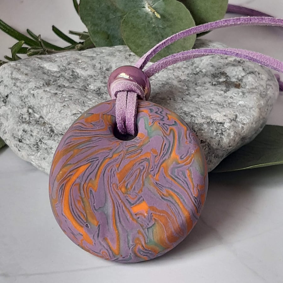 Round pendant in a lilac, orange and sage polymer clay mix