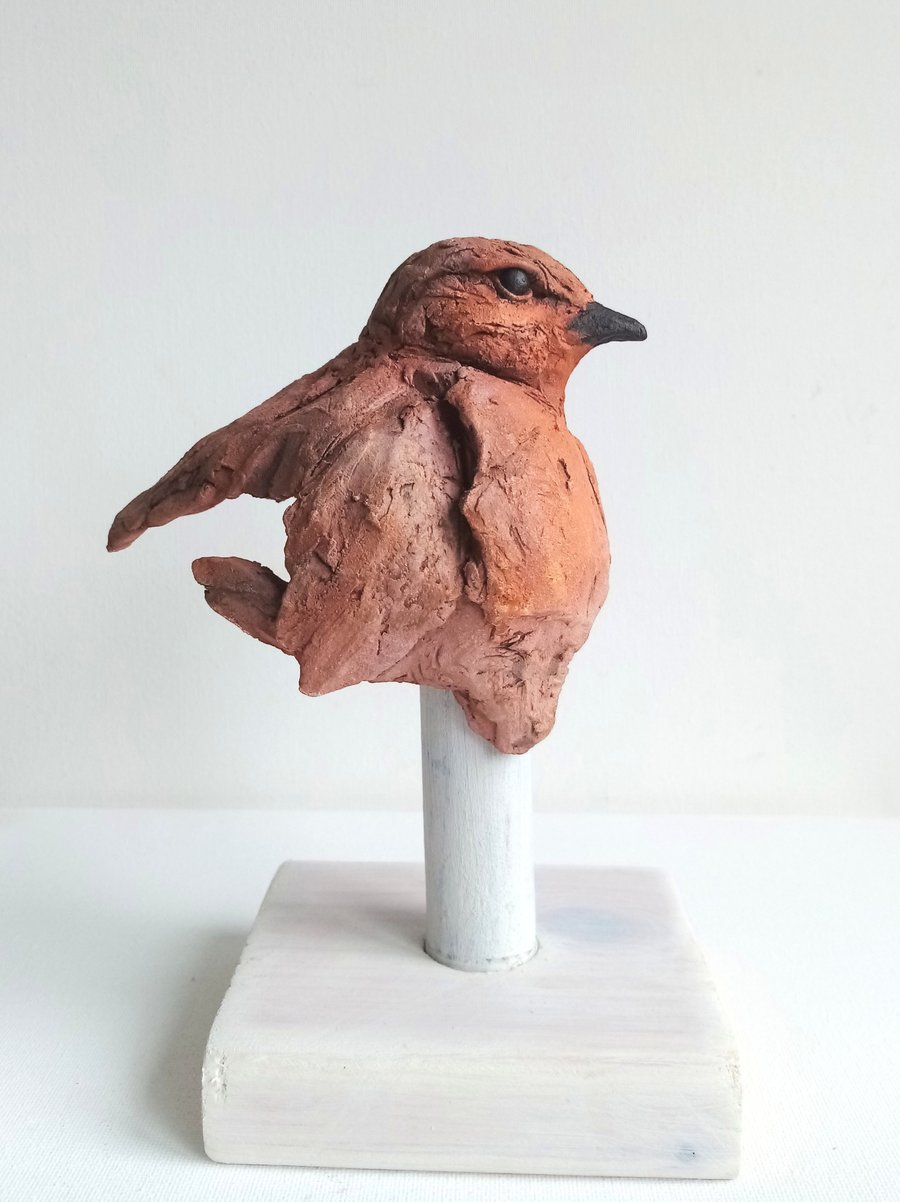 Robin sketch sculpture on wooden stand. 