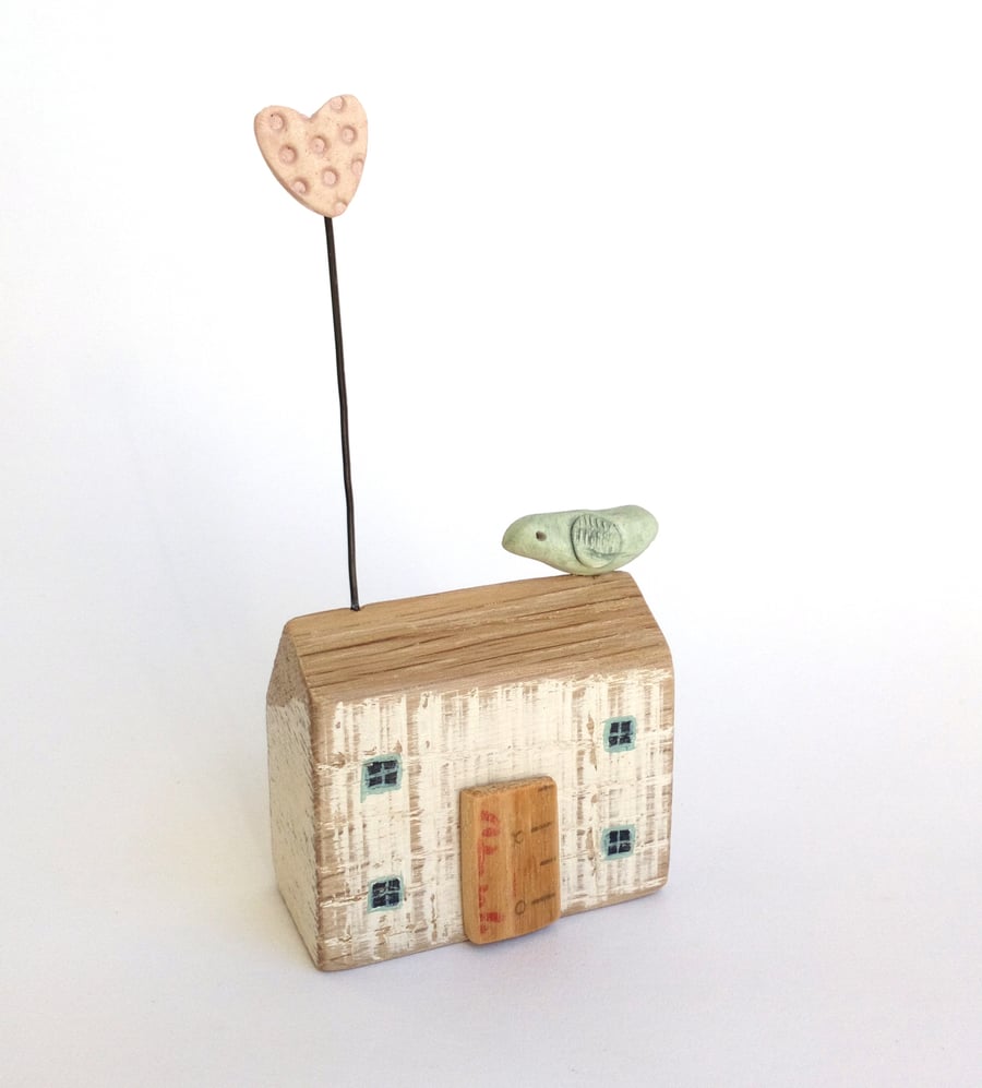 Little wooden house with clay heart and bird