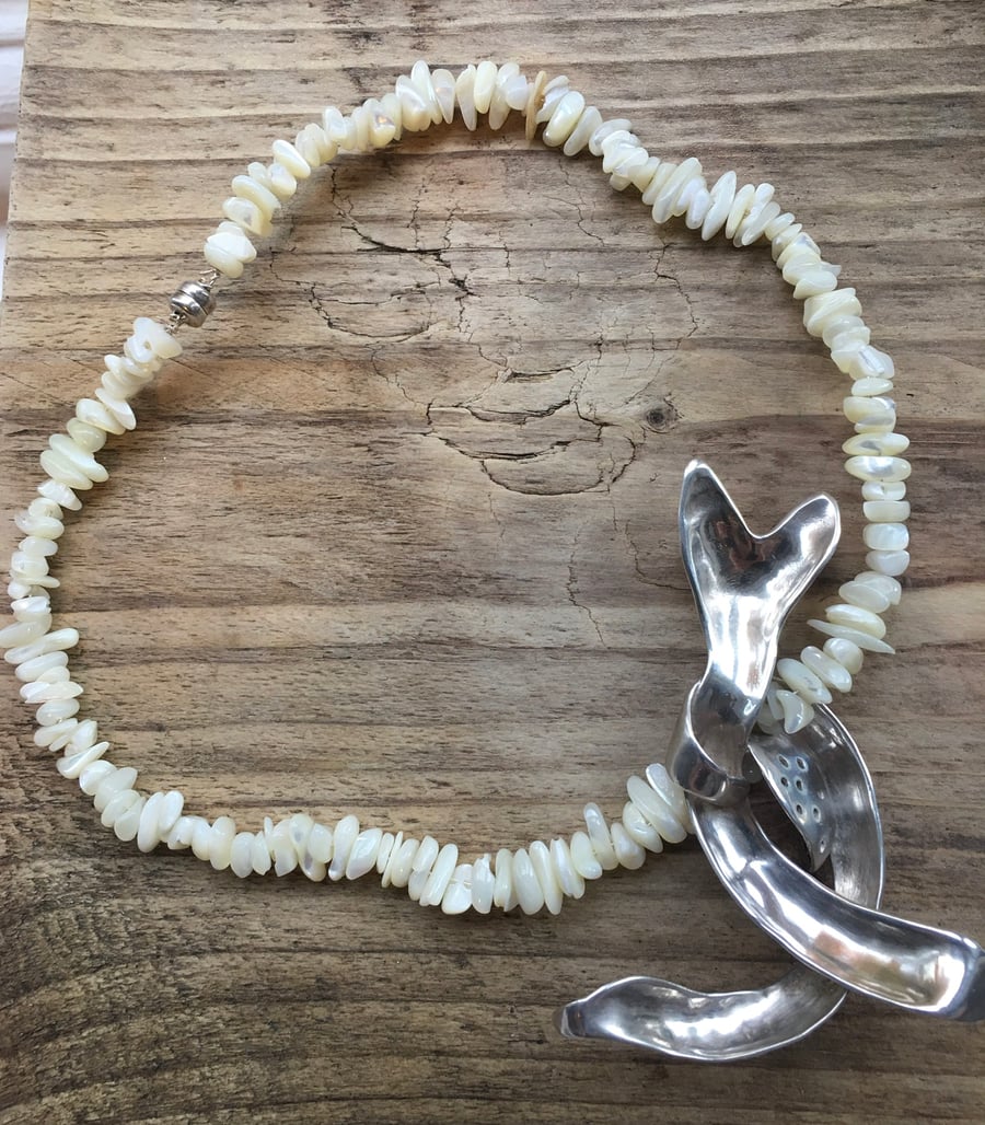 Silver pendant on mother of pearl beads.