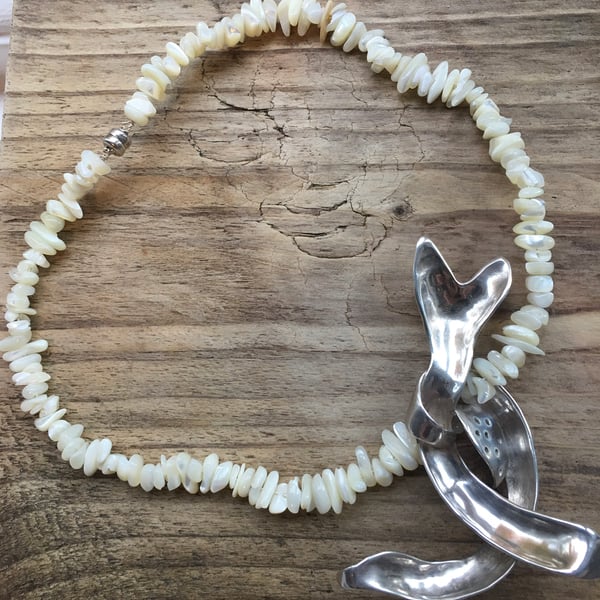 Silver pendant on mother of pearl beads.