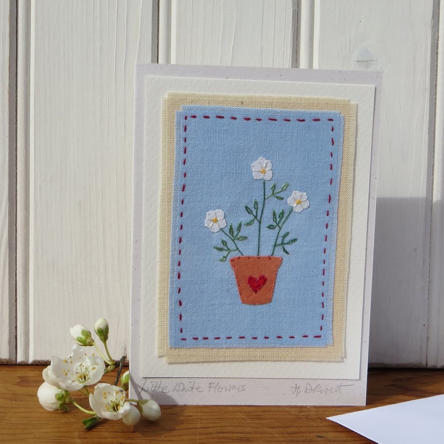Hand-stitched little white  flowers in a pot with embroidered leaves 