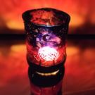 Handmade glass painted tea light candle holder with row of naked trees on sunset