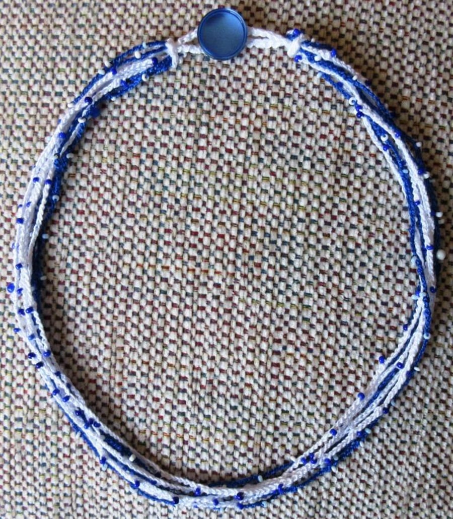 A crocheted necklace in blue and white crochet cotton with tiny beads