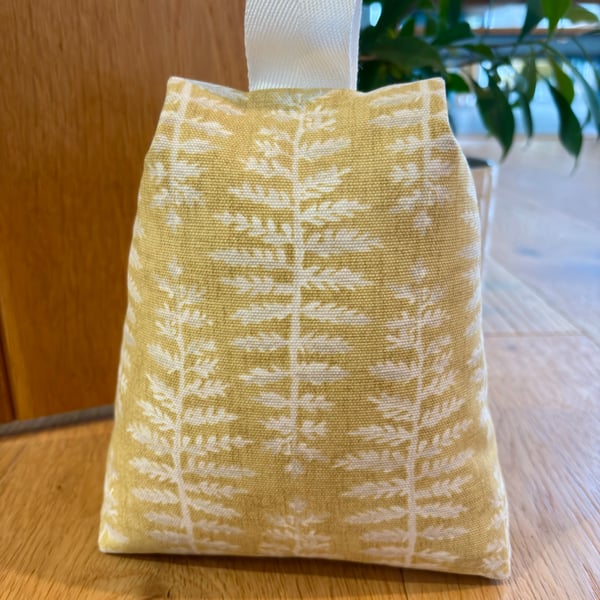Cotton fabric doorstop in mustard with cream fern print, filled with pebbles
