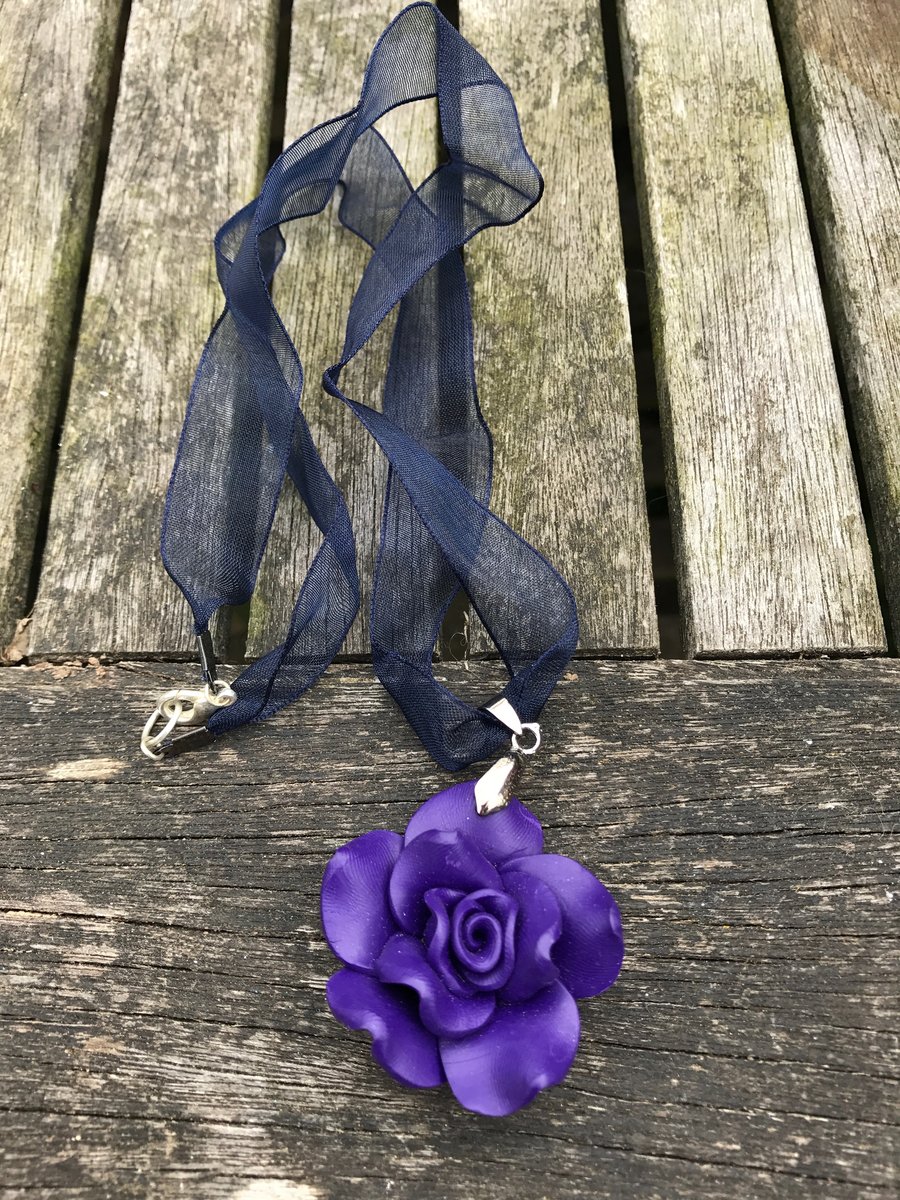 Purple polymer clay flower on dark blue ribbon