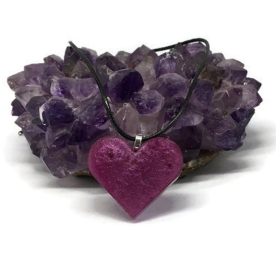 Magenta-purple heart pendant on black cord chain.