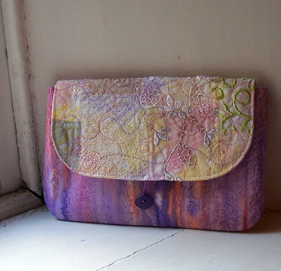 Machine and hand embroidered textile clutch bag with button fastening