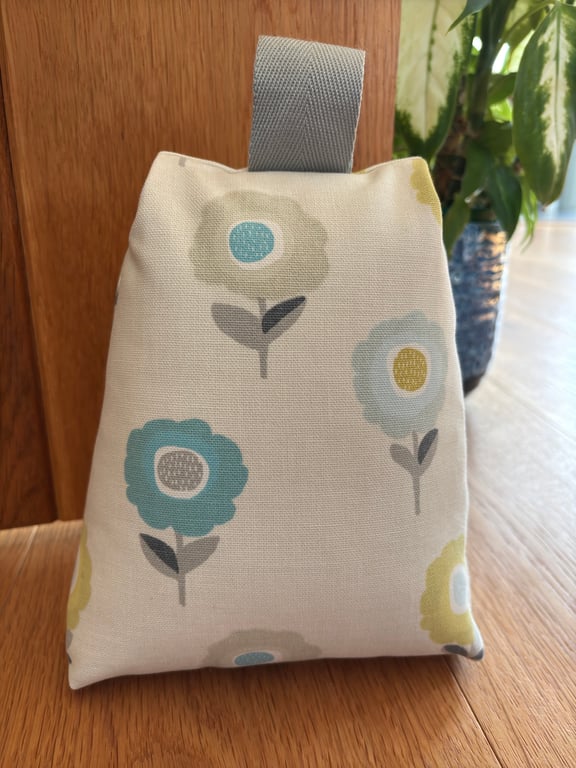 Cotton fabric doorstop in cream with bright floral pattern, filled with pebbles.