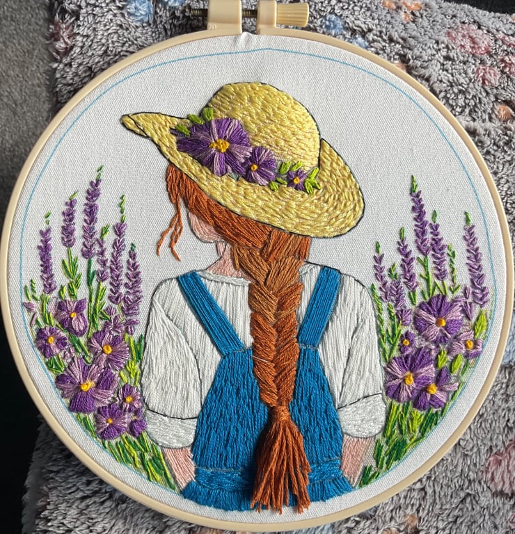 A girl with flowing hair and straw hat in a flower field