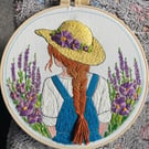 A girl with flowing hair and straw hat in a flower field