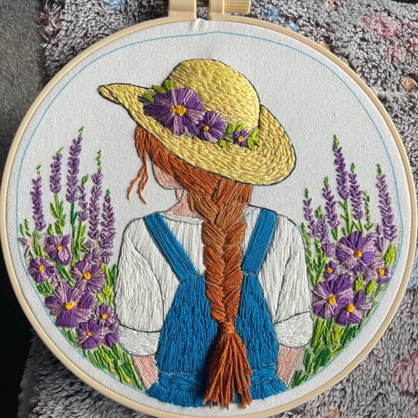 A girl with flowing hair and straw hat in a flower field