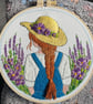 A girl with flowing hair and straw hat in a flower field