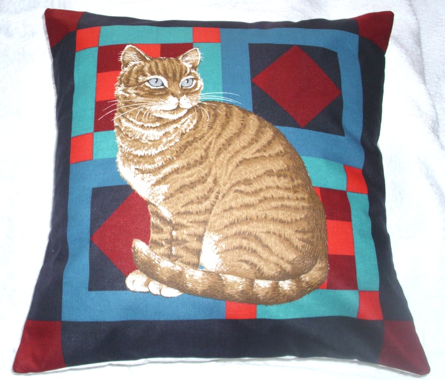 Ginger Tabby cat sitting on a multi coloured background cushion