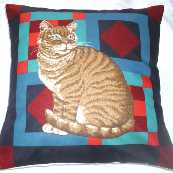 Ginger Tabby cat sitting on a multi coloured background cushion