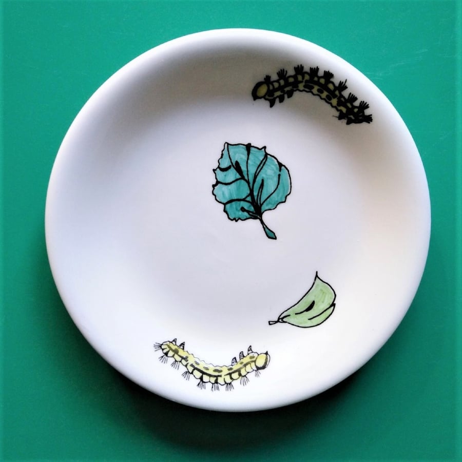 Small shallow dish, hand decorated with two leaves and two caterpillars,