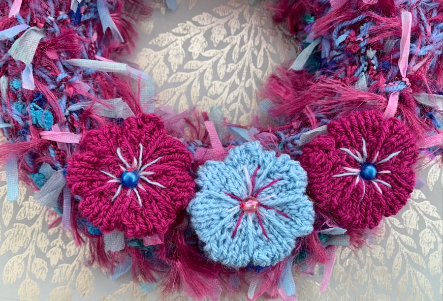 Knitted flower wreath  on knitted ribbon base 