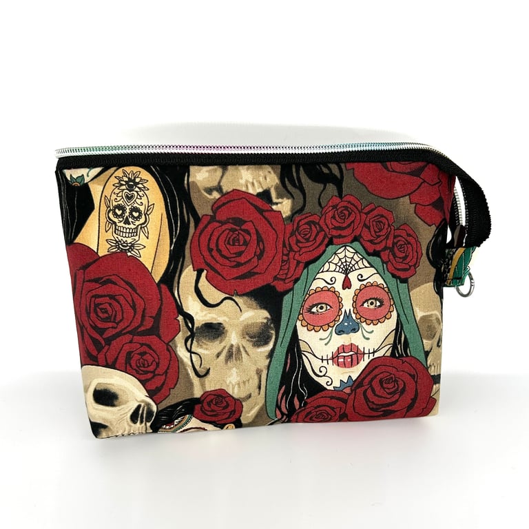 Cosmetic bag with sugar skulls and roses fabric lined with black fabric.