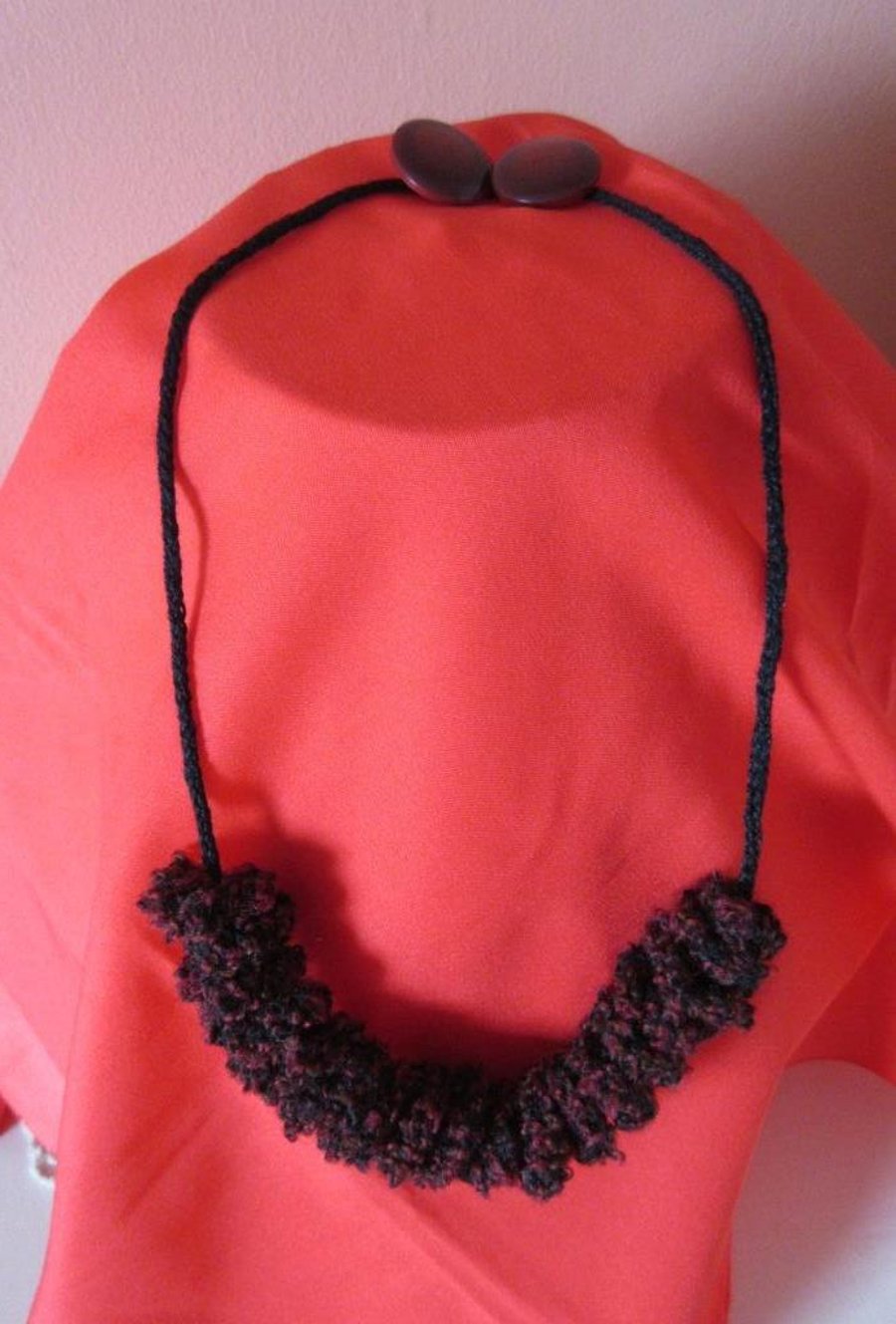 A knitted necklace: a spiral knitted in bobbly yarn threaded on a knitted i-cord