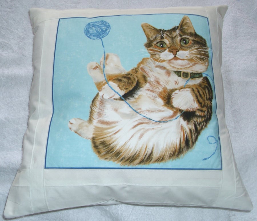 reclining tabby cat with ball of wool cushion