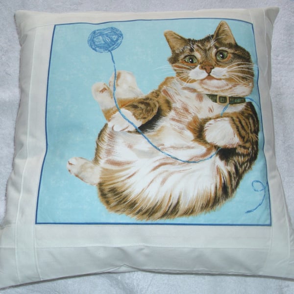 reclining tabby cat with ball of wool cushion