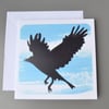Silhouette of bird in flight card with painted blue background