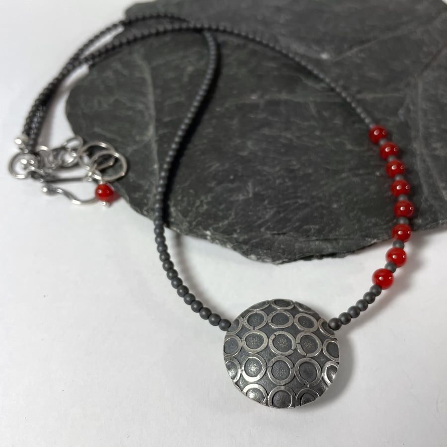 Oxidised Sterling silver pendant on hematite and carnelian bead necklace.