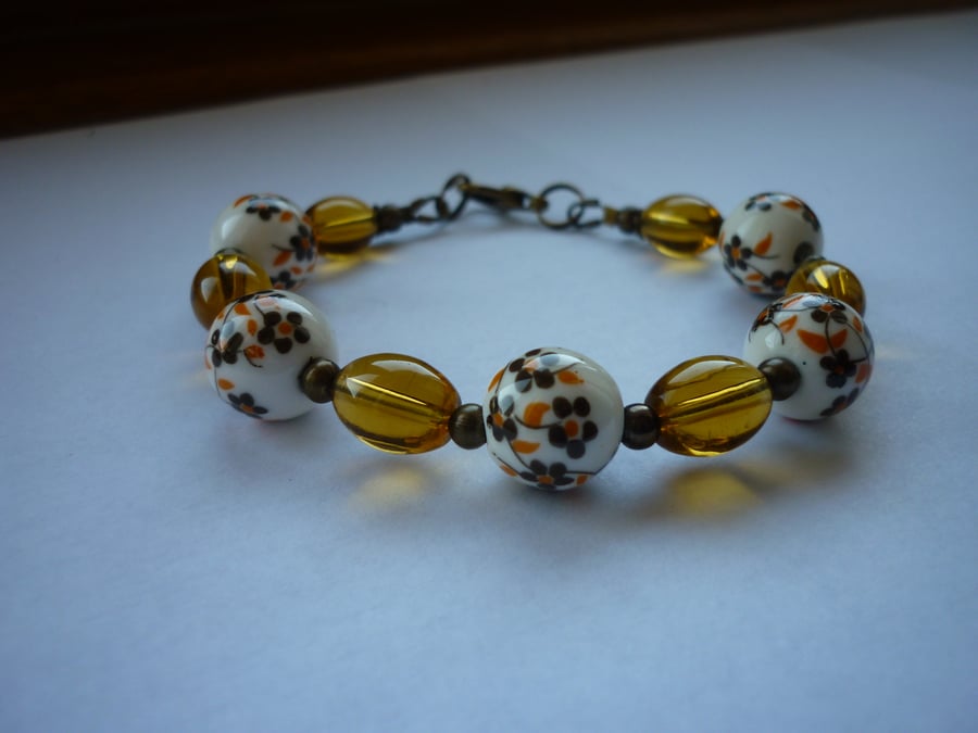 BROWN, WHITE, GOLDEN AMBER AND BRONZE CERAMIC BEAD BRACELET.  