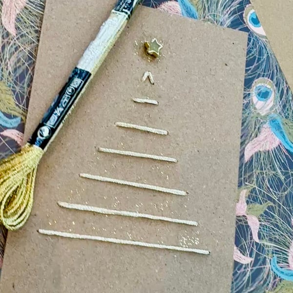 Christmas card of a gold embroidered tree with star, glitter. Natural recycled