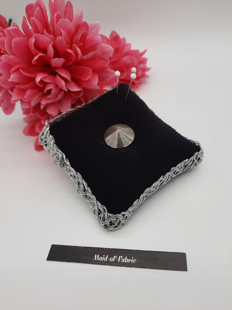 Pin cushion in black corduroy with silver trim and button.