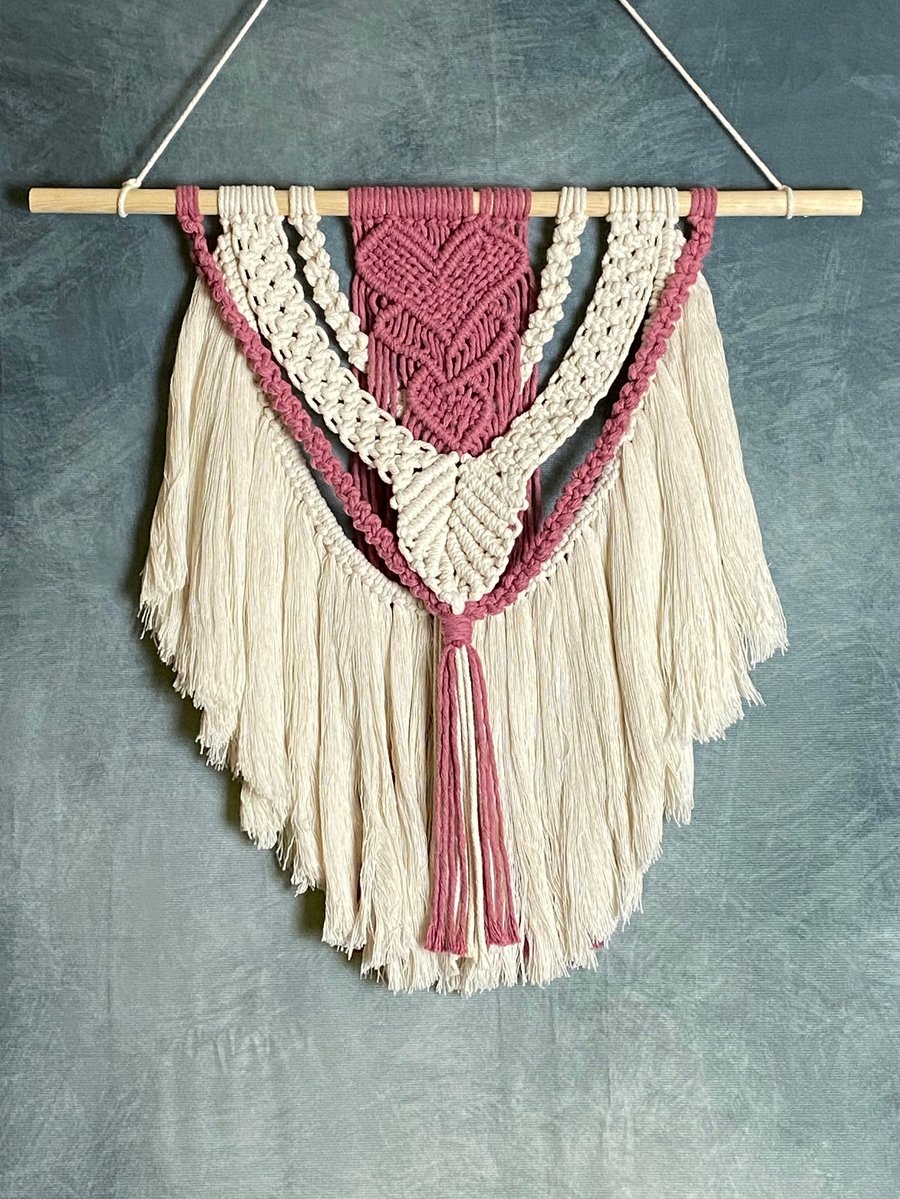 Macrame wall hanging with intricate pink heart knot design
