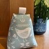 Cotton fabric doorstop in seafoam with white bird print, filled with pebbles.