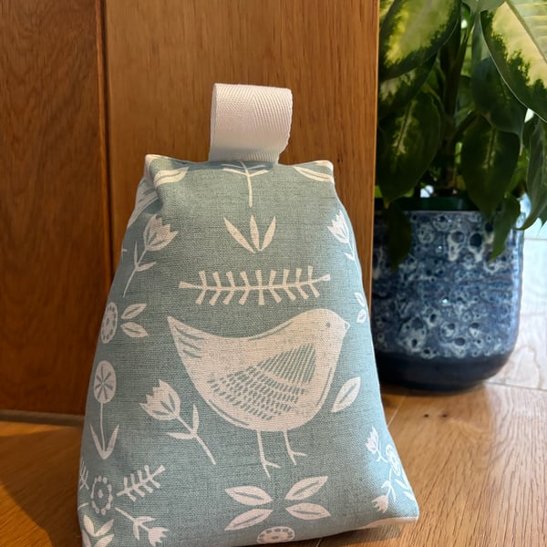 Cotton fabric doorstop in seafoam with white bird print, filled with pebbles.