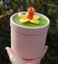 Pink cardboard cylindrical container topped with hand knitted daffodil